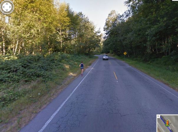 Ditch on one side, blackberries on the other. Runner in the road.